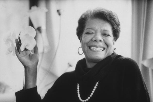 8th January 1993:  Headshot portrait of African-American author Maya Angelou wearing black sweater with a pearl necklace, smiling and holding flowers in one hand.  (Photo by Stephen Matteson Jr/New York Times Co./Getty Images)